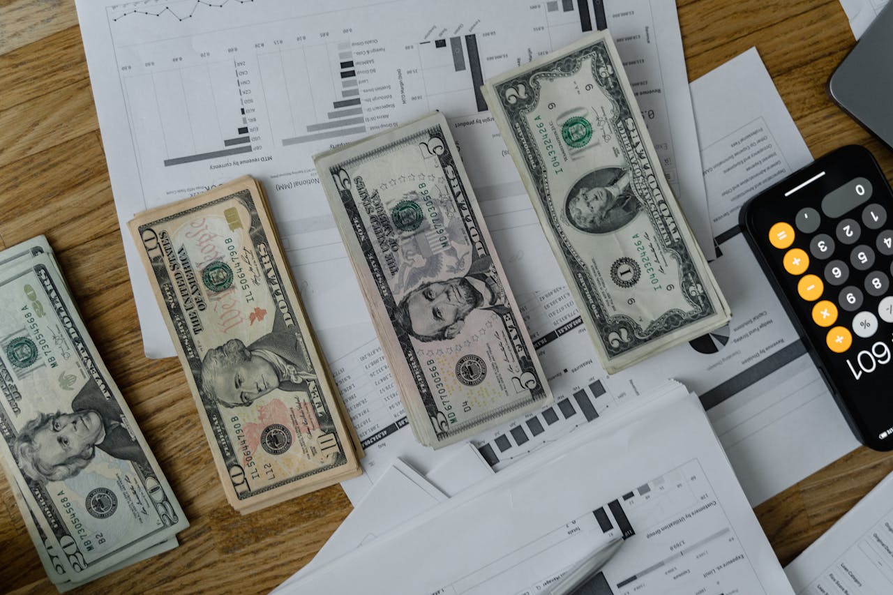 A workspace setup featuring cash, documents, and a calculator symbolizing financial analysis and budgeting.